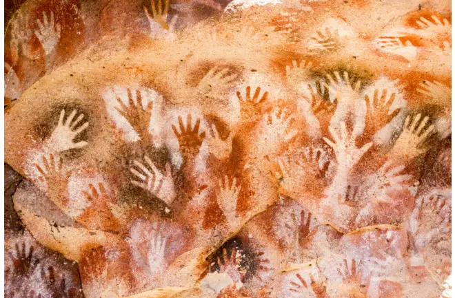 Ancient cave art of many hand prints.